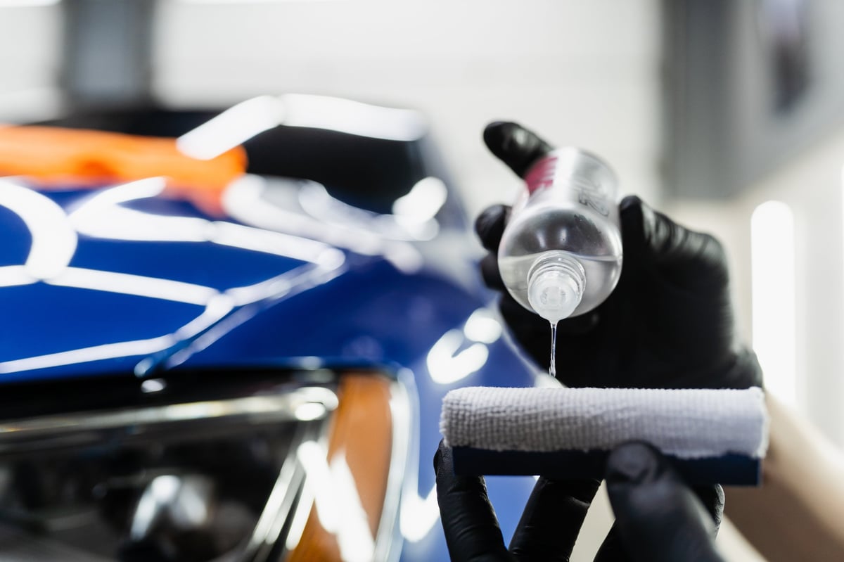Detailing service worker applies ceramic protective liquid on sponge close-up