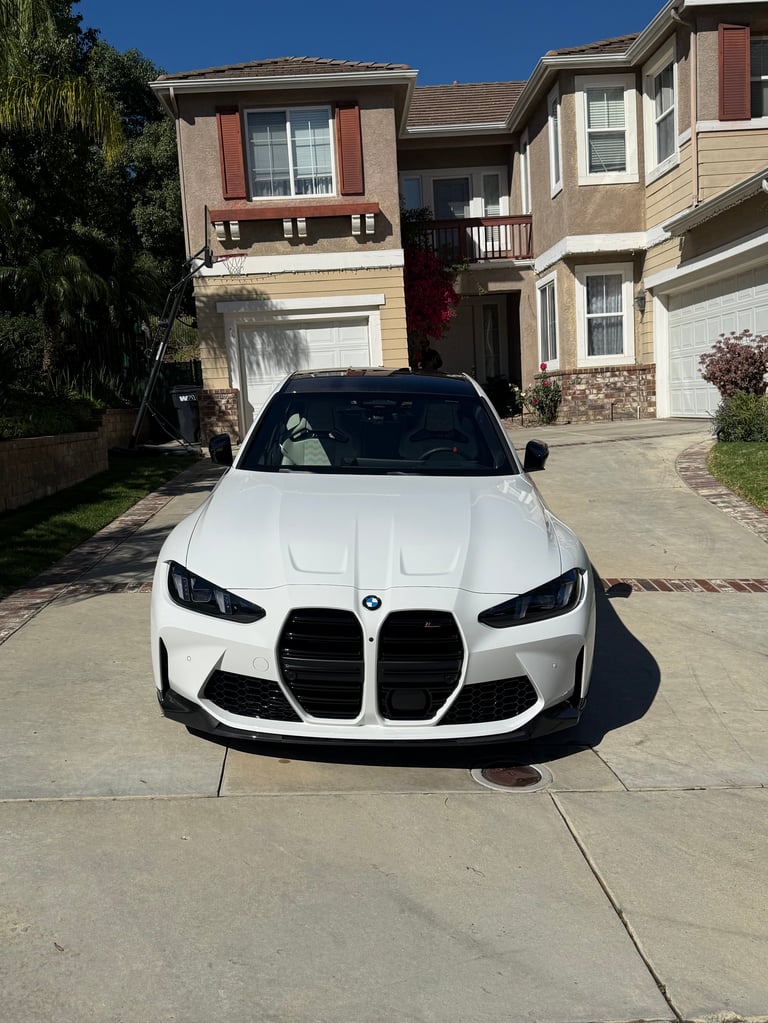 White BMW M340i parked on residential driveway with two-story house in background